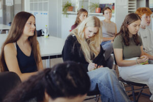 Auf dem Bild sieht man mehrere junge Menschen, welche sich etwas notieren.