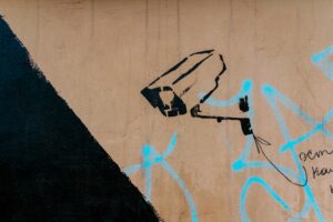 Graffiti mit Überwachungskamera an einer Hauswand.