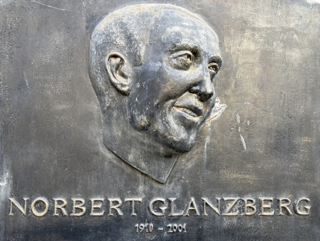 Das Bild zeigt die Gedenktafel für Norbert Glanzberg, mit einem Portrait von ihm.
